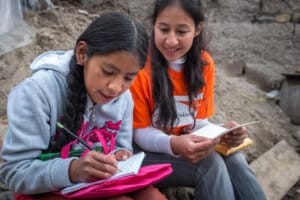 Une petite fille parrainée a reçu une lettre de son parrain, elle lui rédige sa réponse - World Vision
